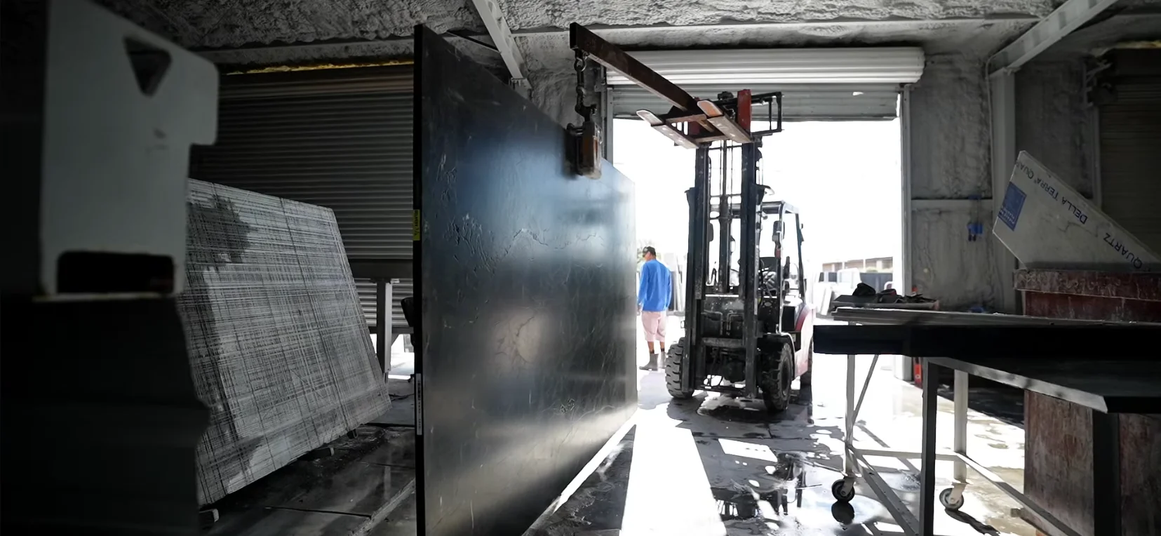 Inside Mirastone's stone fabrication shop with slabs and forklift moving material in Phoenix